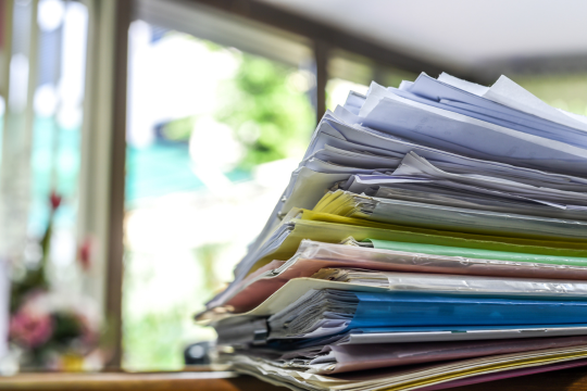 Stack of bills and paperwork on a desk.