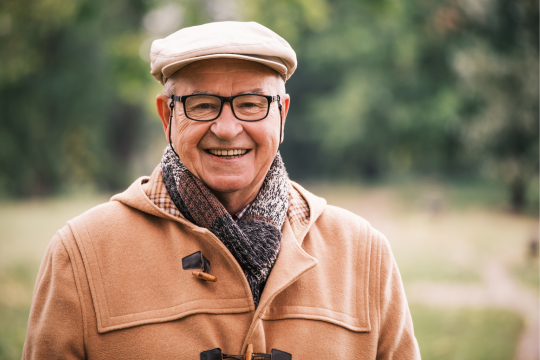 Homme adulte souriant à l’extérieur.