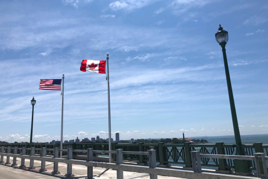 Drapeaux américain et canadien flottant dans le vent côte à côte, au Pont de la Paix.