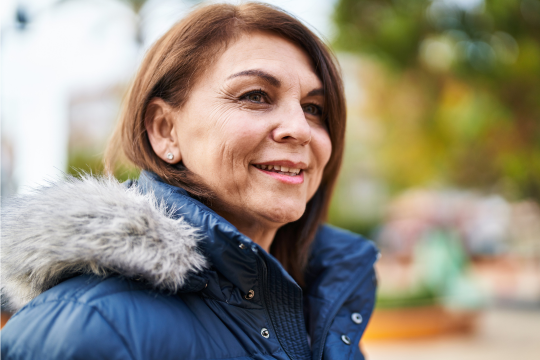 Femme adulte souriante, portant un manteau d’hiver.