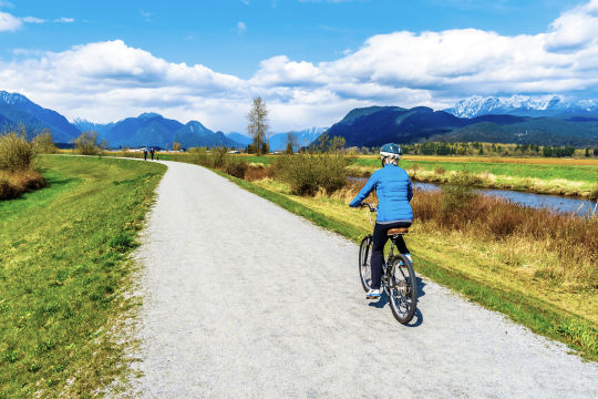 Adult woman biking along the Alouette River in Maple Ridge, British Columbia.